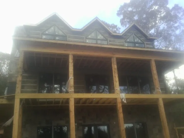 Dormers and porch framing on a large log home under construction — Roof Coating work by our crew in Verona Beach