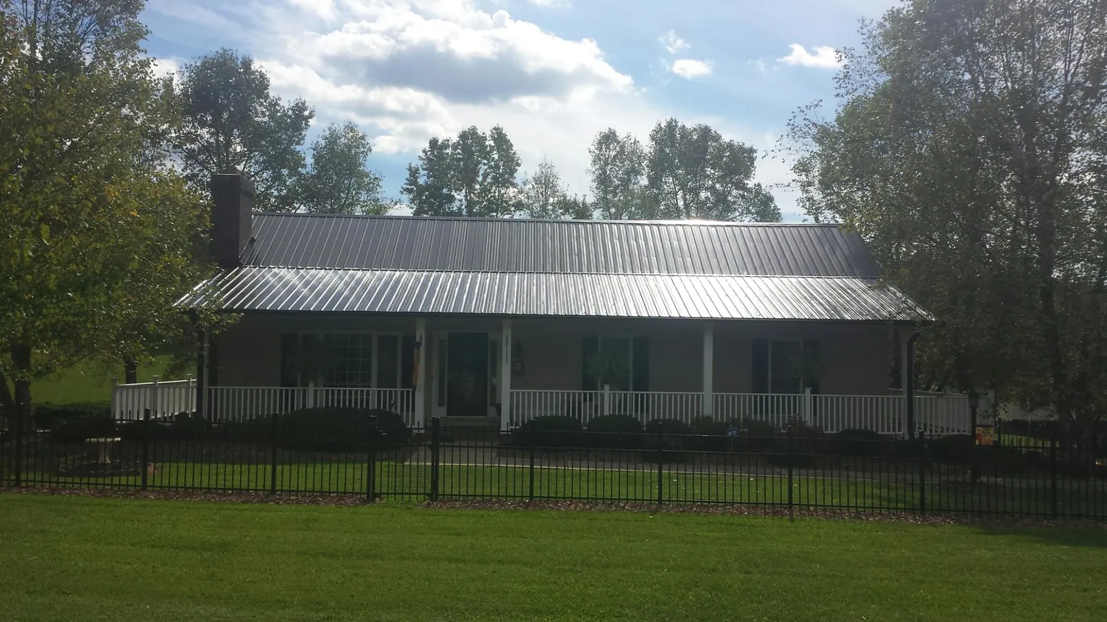 Gray metal roof on a brick ranch with a full width front porch — Gutter Guard Installation work by our crew in Verona Beach