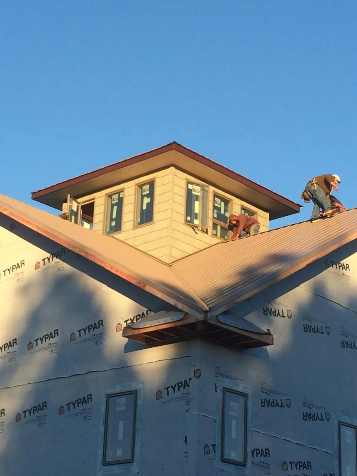 Roofers working around a rooftop cupola on a new metal roof at sunset — Roof Waterproofing in Verona Beach by Roofing Brothers